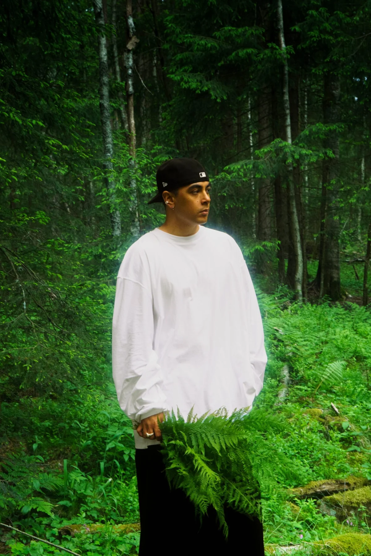 Philip Emilio i hvit genser og svarte bukser fotografert i skogen for EP-en SAINT vol.1