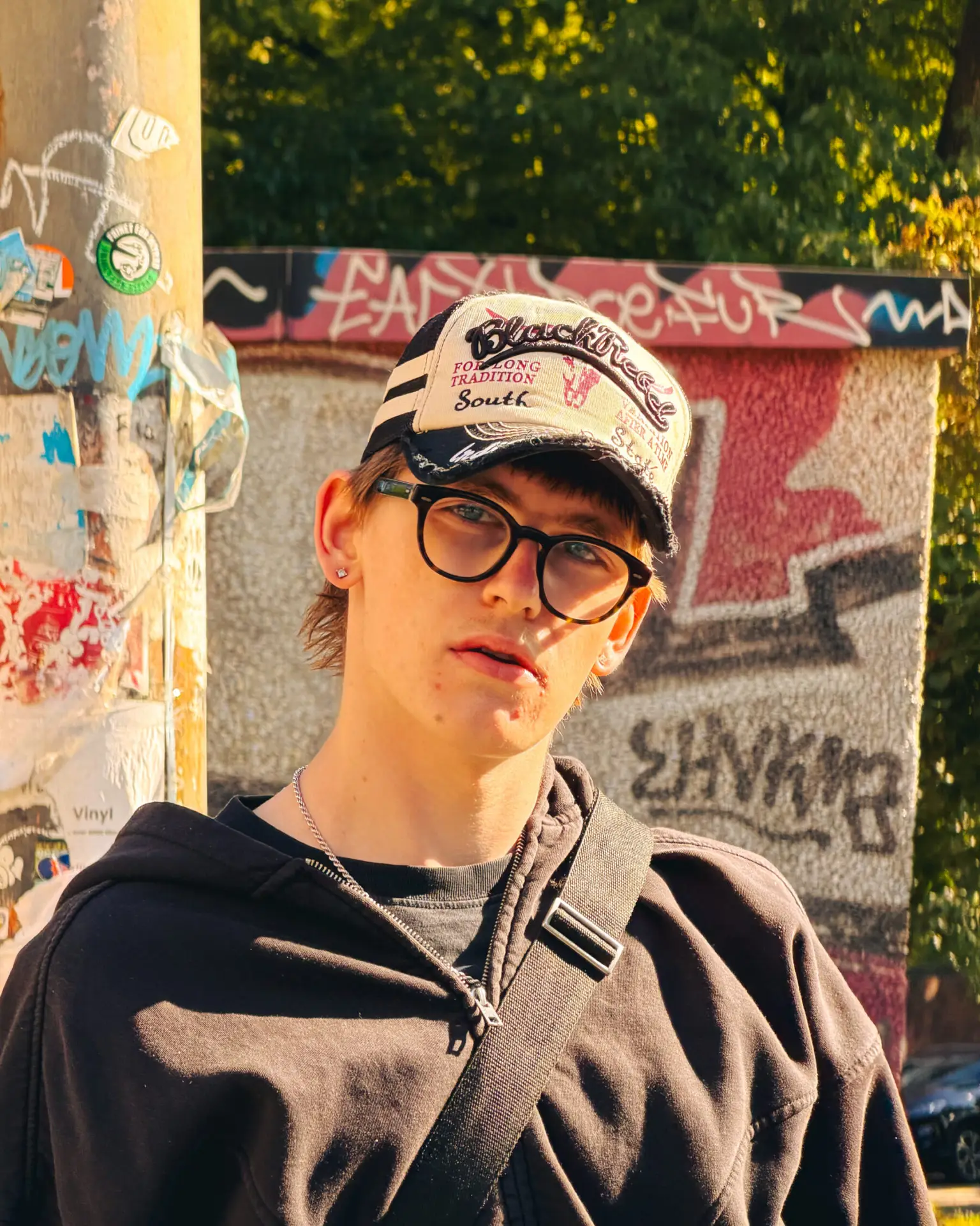 OZZI foran en tagget vegg, portrett